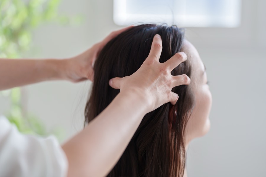 A therapist's hands cradling and supporting a client's head with light, still contact.